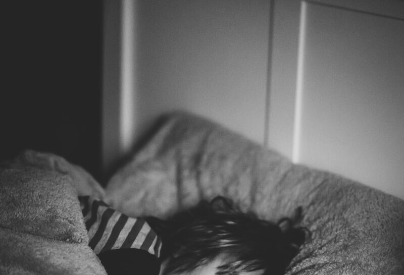 grayscale photography of kid lying on bed